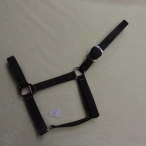 A black harness with white straps on top of a bed.