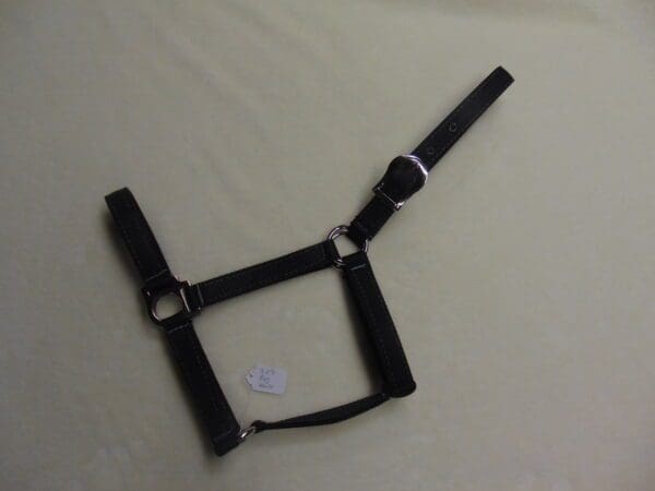 A black harness with white straps on top of a bed.