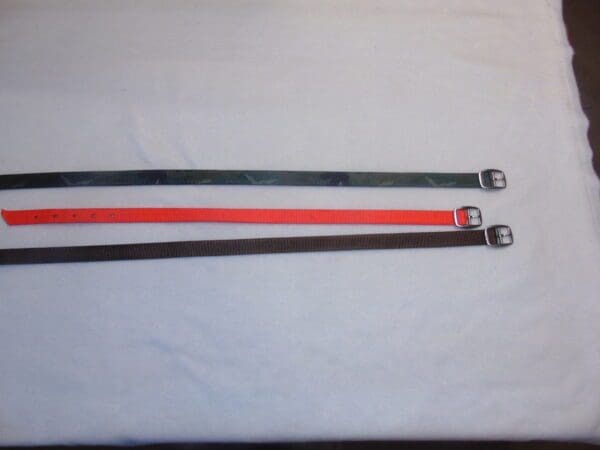 A pair of red and black straps on top of a white sheet.