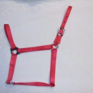 A red harness on top of a white sheet.