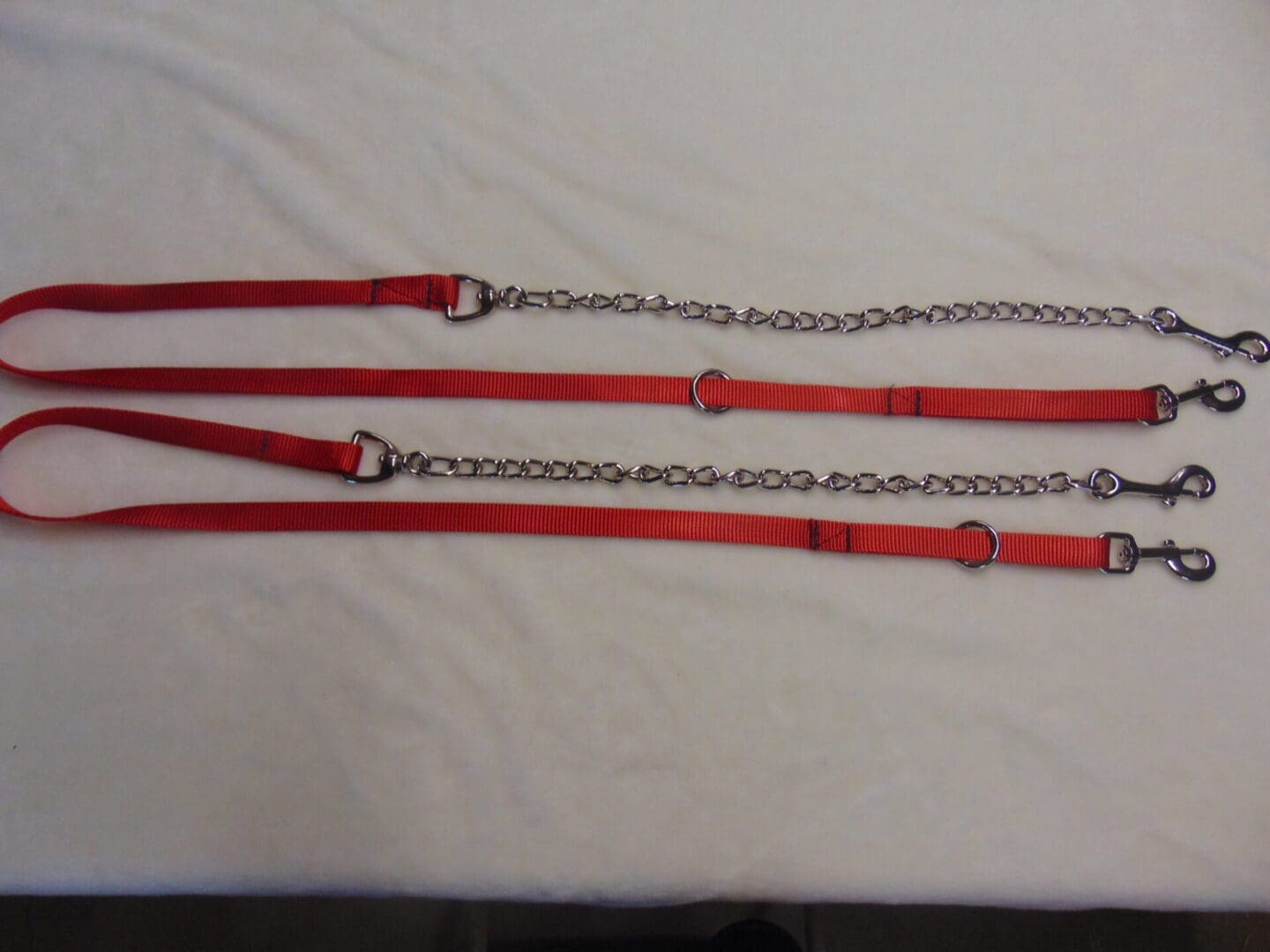 A red leash with two chains and one metal ring.