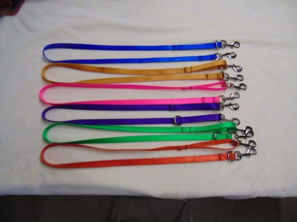 A group of eight different colored leashes on top of a table.