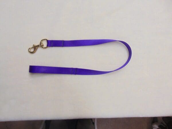 A purple lanyard with gold hardware on top of a table.