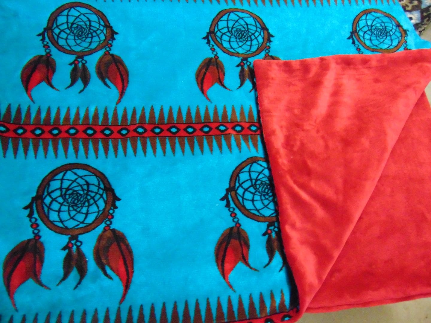 A blanket with red and blue feathers on it