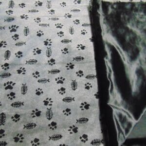 A black and white blanket with fish and paw prints