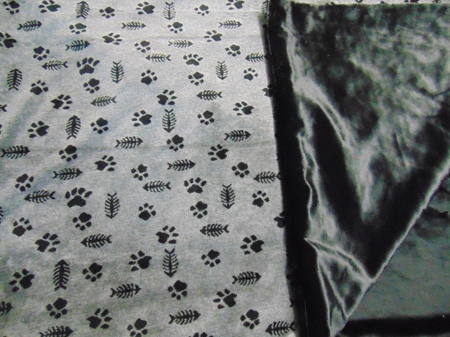 A black and white blanket with fish and paw prints