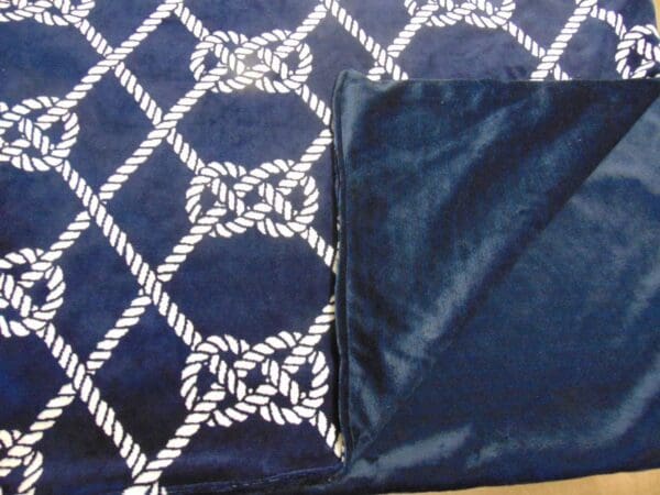 A blanket with white rope and blue squares on it.