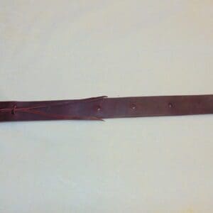 A brown leather strap with two holes on it.