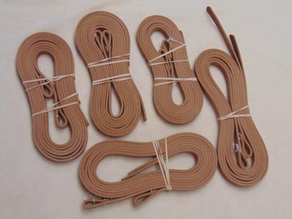 A group of six pairs of brown leather laces.